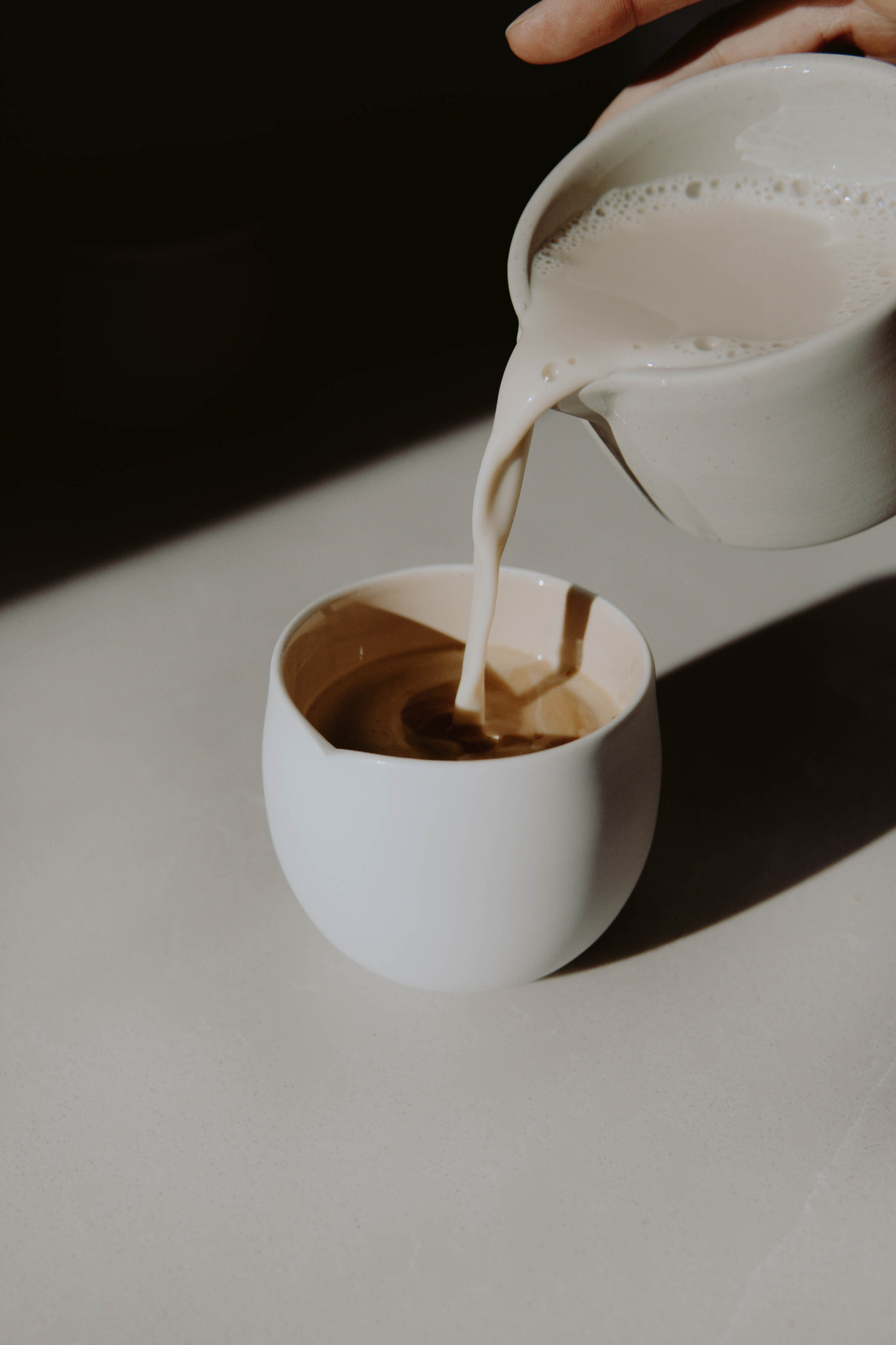 Pouring Over Milk From Serving Pitcher to a Cup